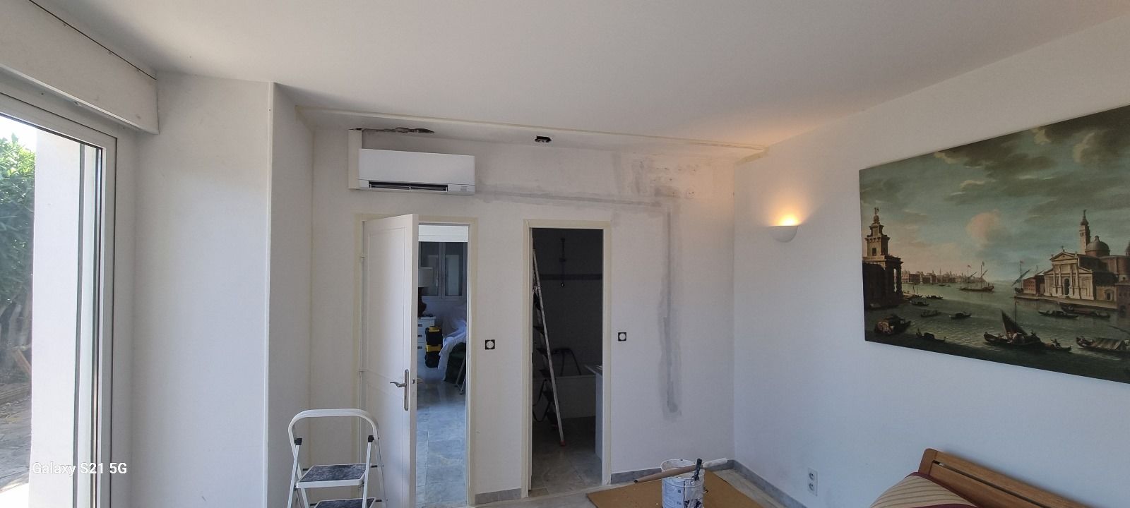 Un salon avec un tableau au mur et une échelle.