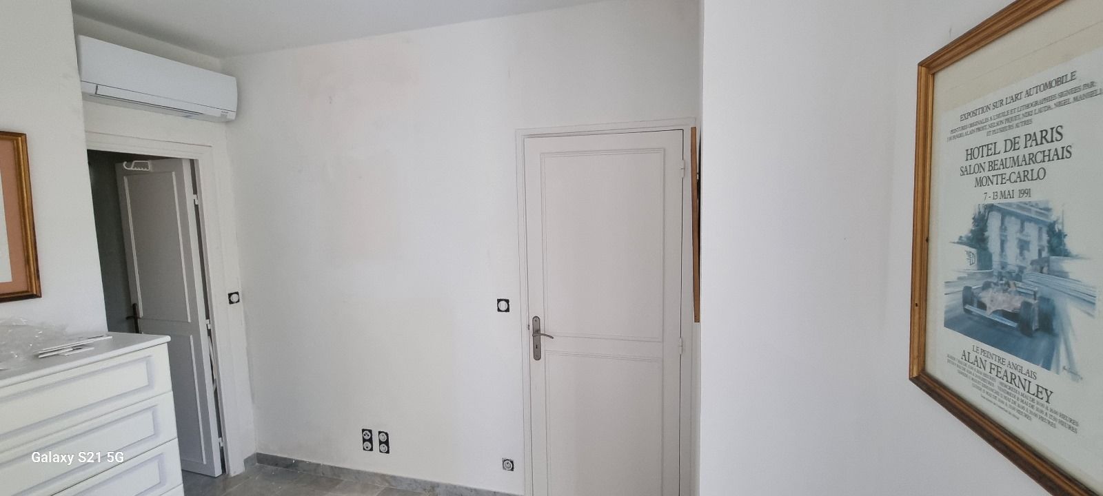 Un couloir avec un tableau sur le mur et une porte.