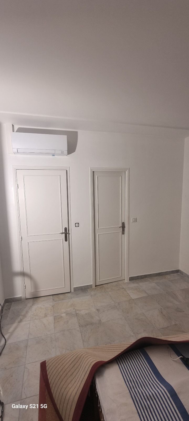 Une chambre avec un lit, deux portes et un ventilateur de plafond.