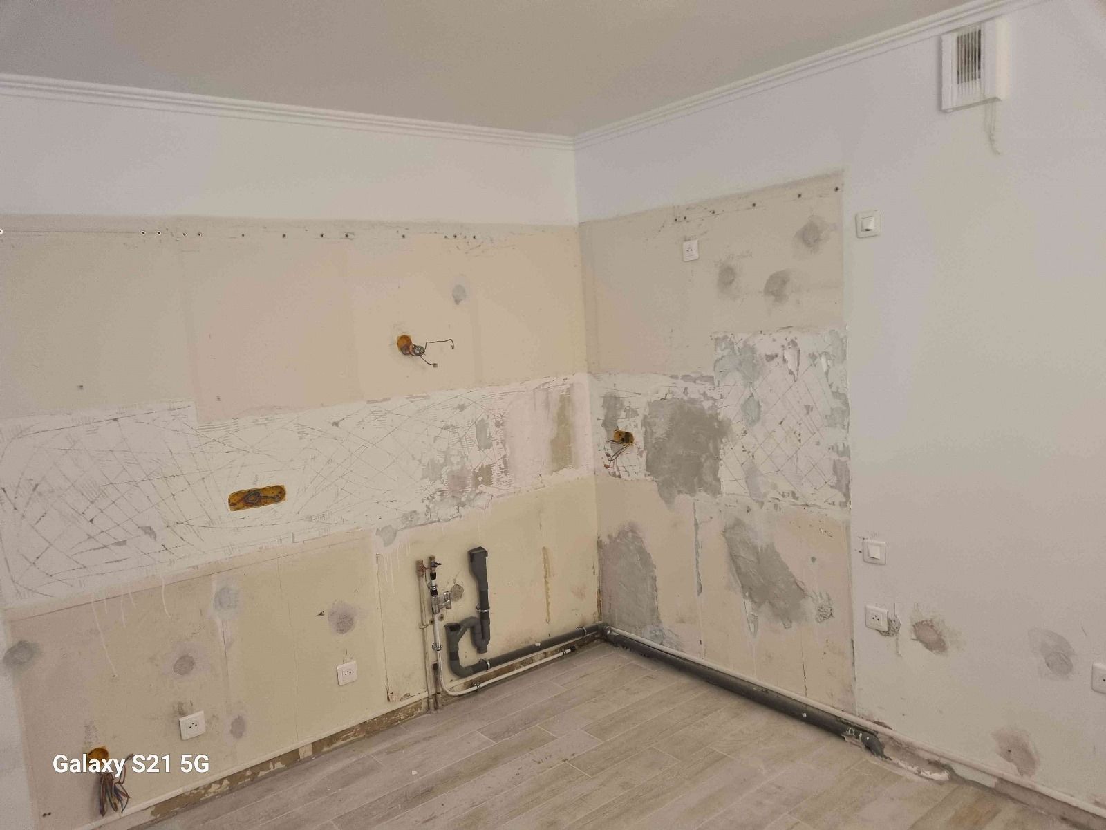 Une cuisine aux murs blancs et au sol en bois est en cours de rénovation.