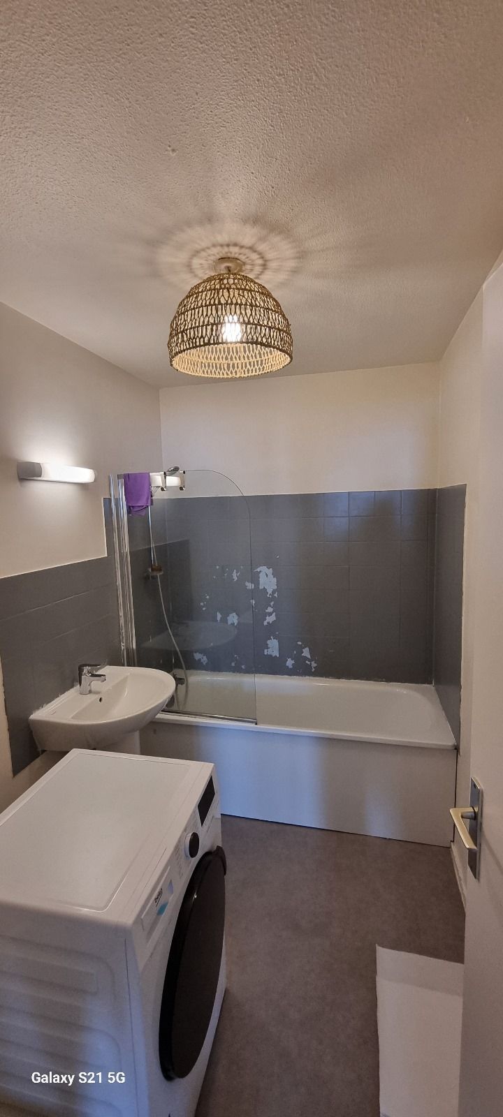 Une salle de bain avec machine à laver, lavabo et baignoire.