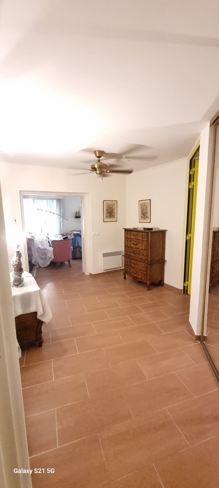 Un salon avec un ventilateur de plafond et une commode.