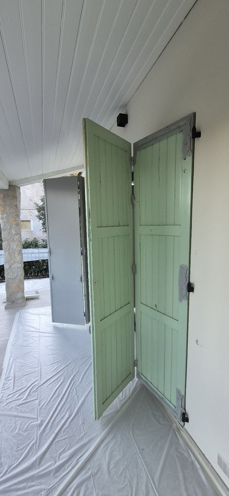 Une porte verte est ouverte sur un mur blanc.