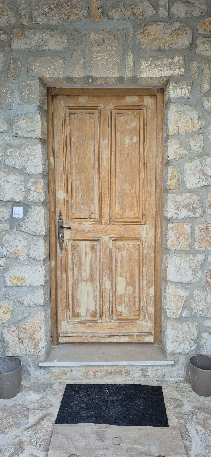 Une porte en bois se trouve devant un mur de pierre.