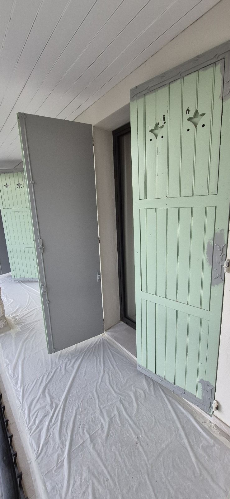 Une porte est en train d'être peinte dans une pièce avec un drap blanc sur le sol.