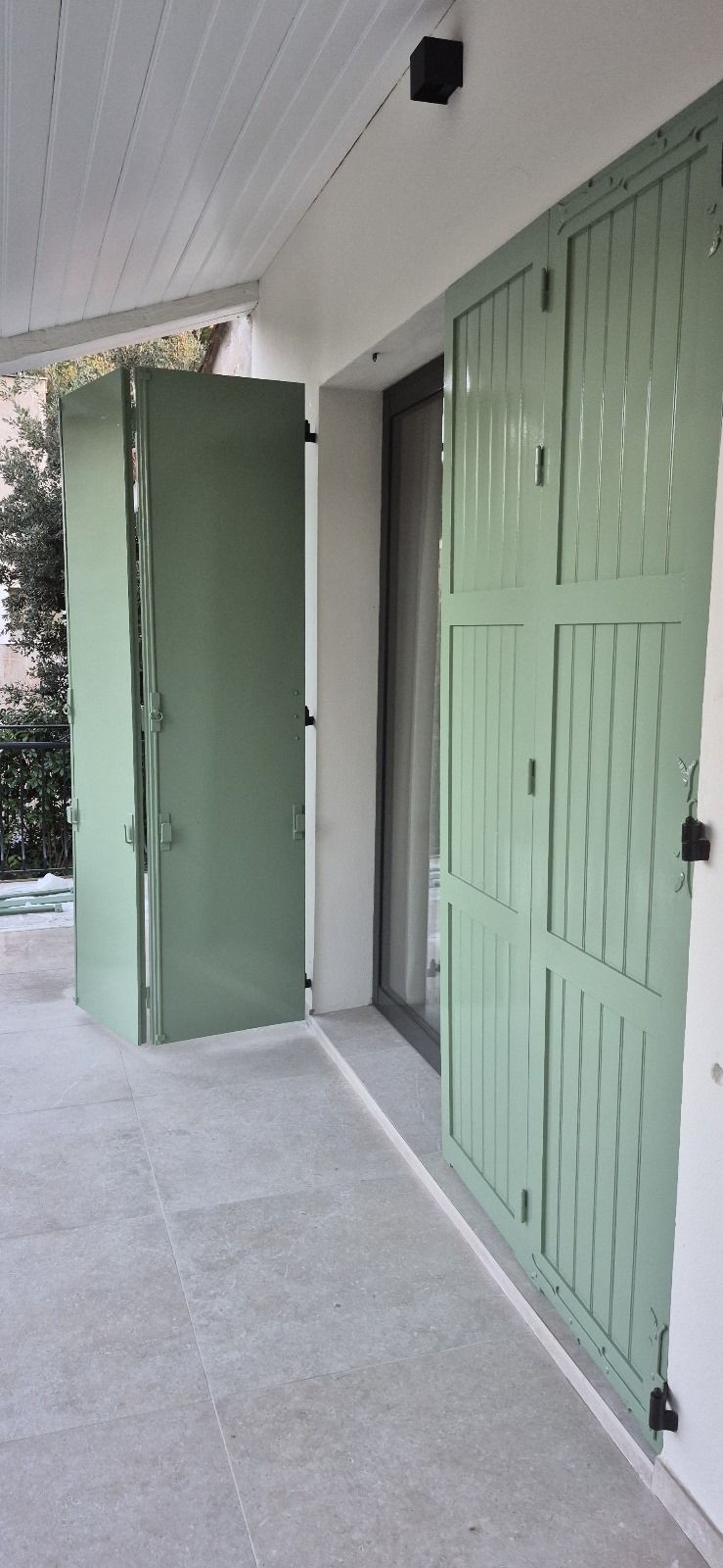 Une maison avec des volets verts aux fenêtres et aux portes.