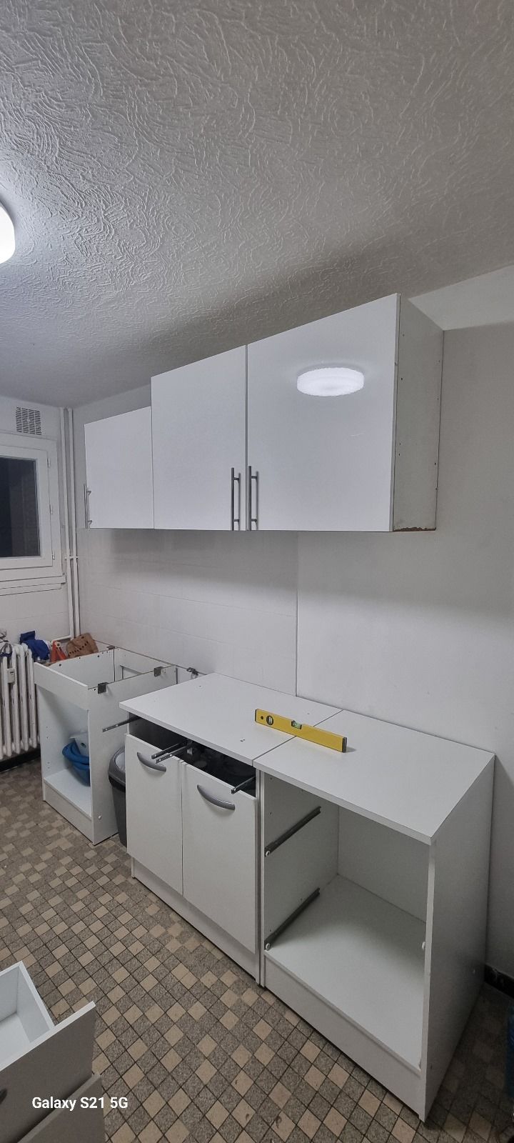 Une cuisine avec des armoires blanches et une règle jaune sur le comptoir.