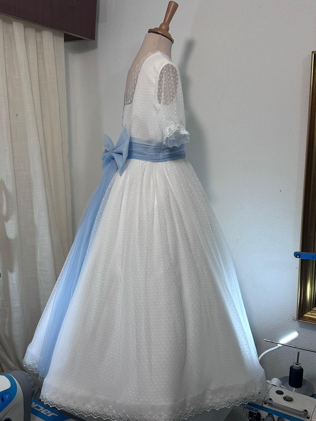 Un vestido blanco y azul está sobre un maniquí en una habitación.