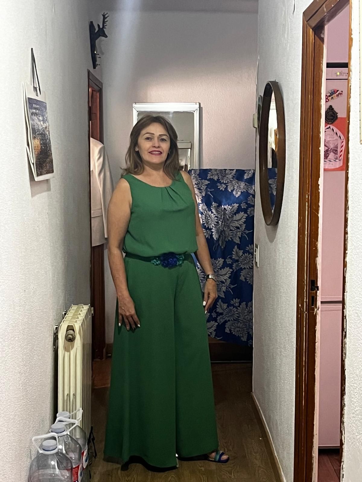 Una mujer con un vestido verde está parada en un pasillo.