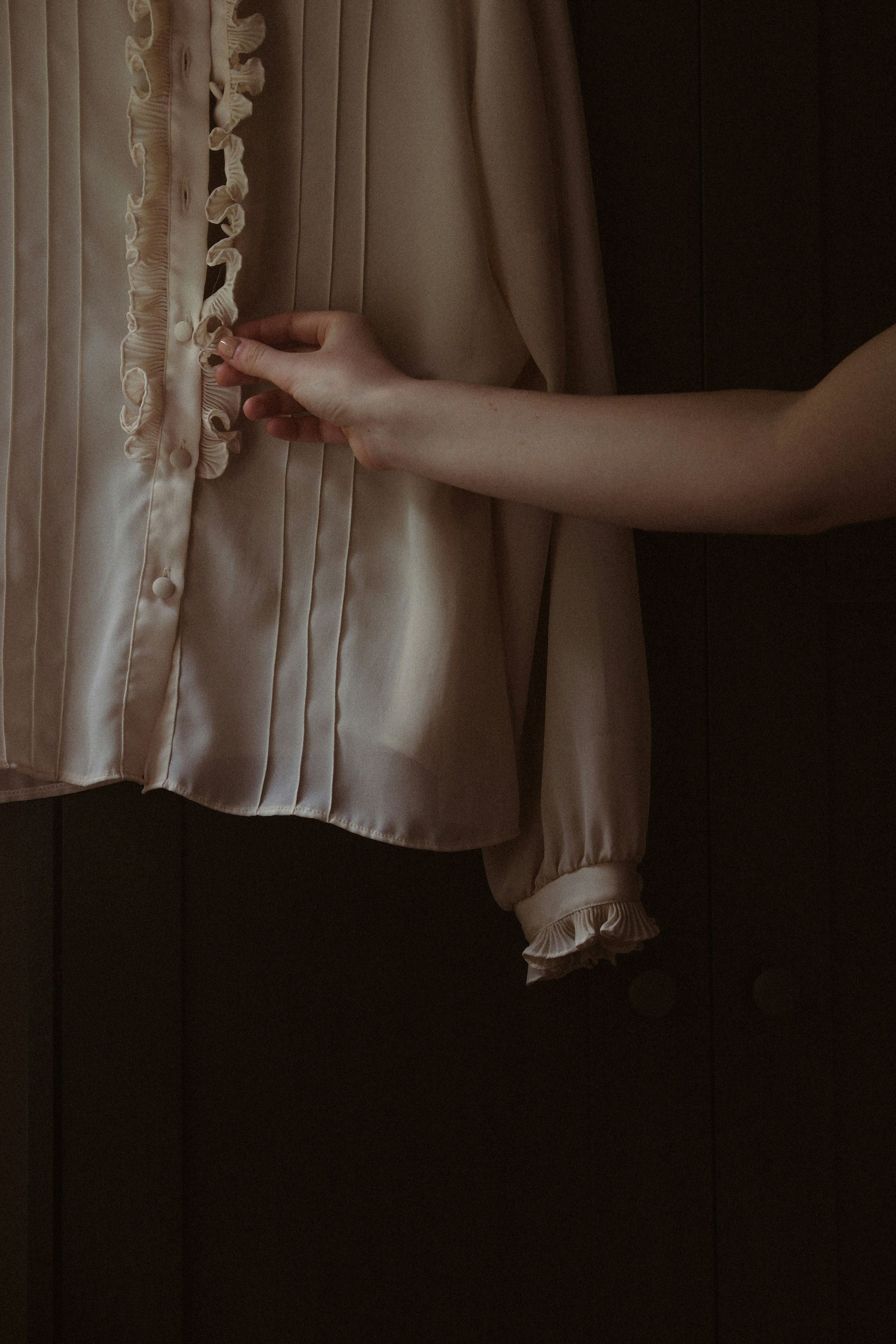 Una mujer sostiene una camisa blanca en su mano.