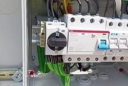 Panel eléctrico con interruptores y disyuntores, cables conectados.