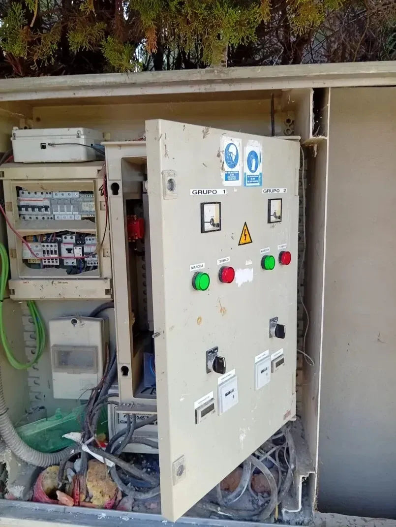 Panel eléctrico abierto con interruptores, luces y cableado.