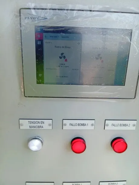 Panel de control con pantalla, botones y luces. Colores plateado y rojo. Botones etiquetados con texto.