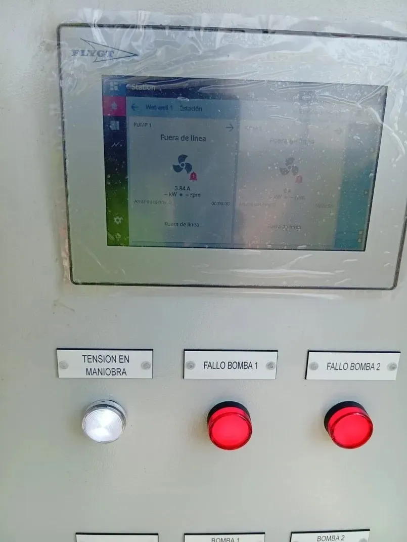 Panel de control con pantalla táctil que muestra una interfaz, tres botones etiquetados debajo y luces indicadoras.