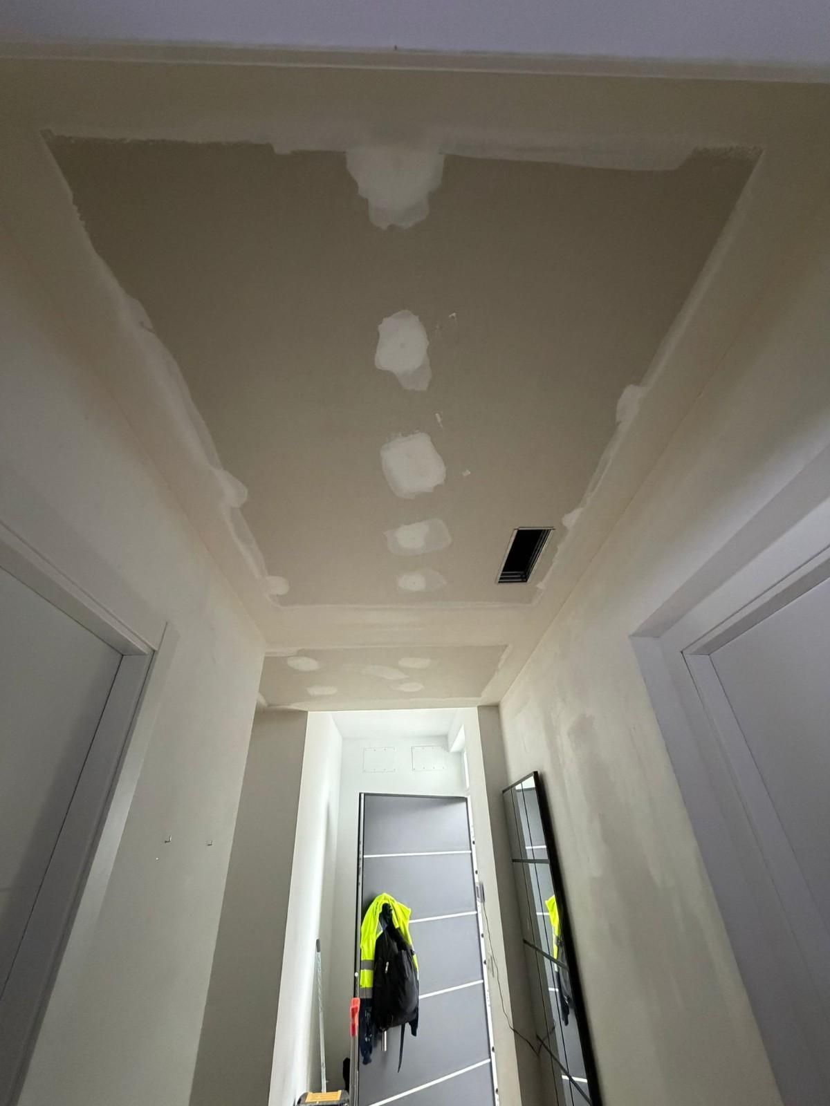 Techo del pasillo con zona empotrada y ventilación. Se ven manchas de yeso. Puertas laterales.