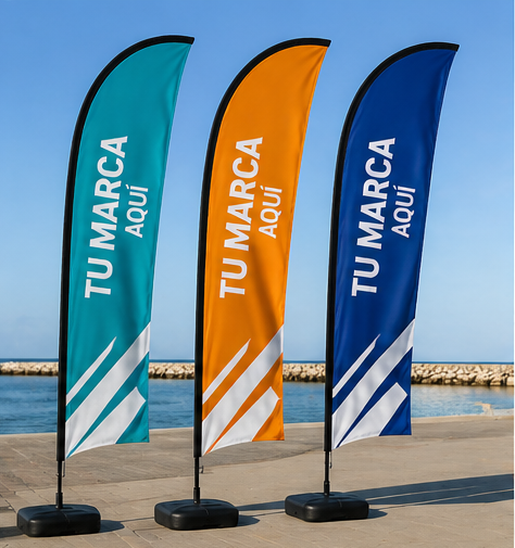 Tres banderas de plumas con el logotipo de la marca, en color turquesa, naranja y azul, ondean en un soleado paseo marítimo.