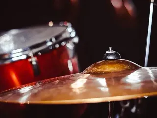 Primer plano de una batería: bombo rojo y platillo dorado.