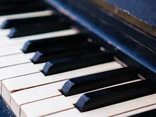 Primer plano de las teclas de un piano, en blanco y negro. Algunas teclas están pulsadas.