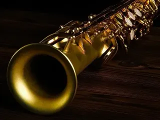 Saxofón dorado sobre una superficie de madera oscura.