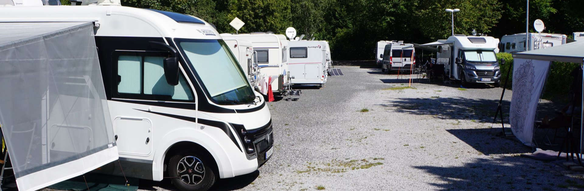 Stellplätze für Wohnmobile mit Ausblick - Reisemobilhafen Twistesee Eine Reihe Wohnmobile sind auf einem Feld geparkt.