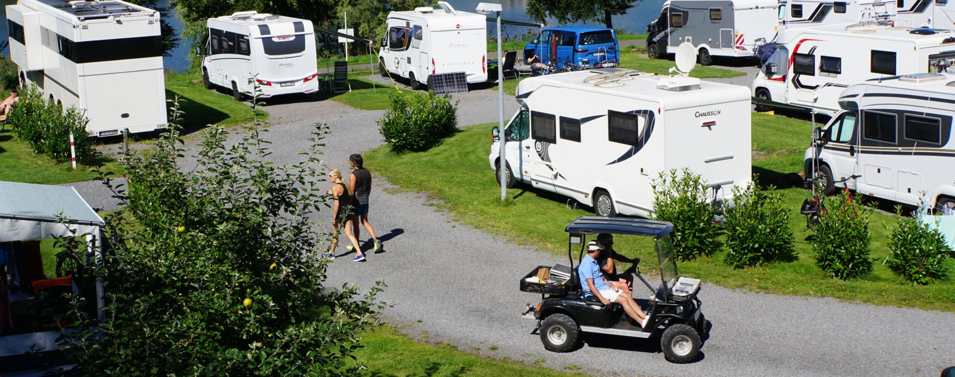 Eine Reihe Wohnmobile sind auf einem Feld geparkt.