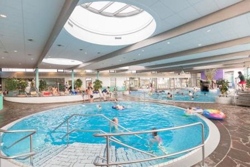 Ein großes Hallenbad mit Leuten, die darin schwimmen.