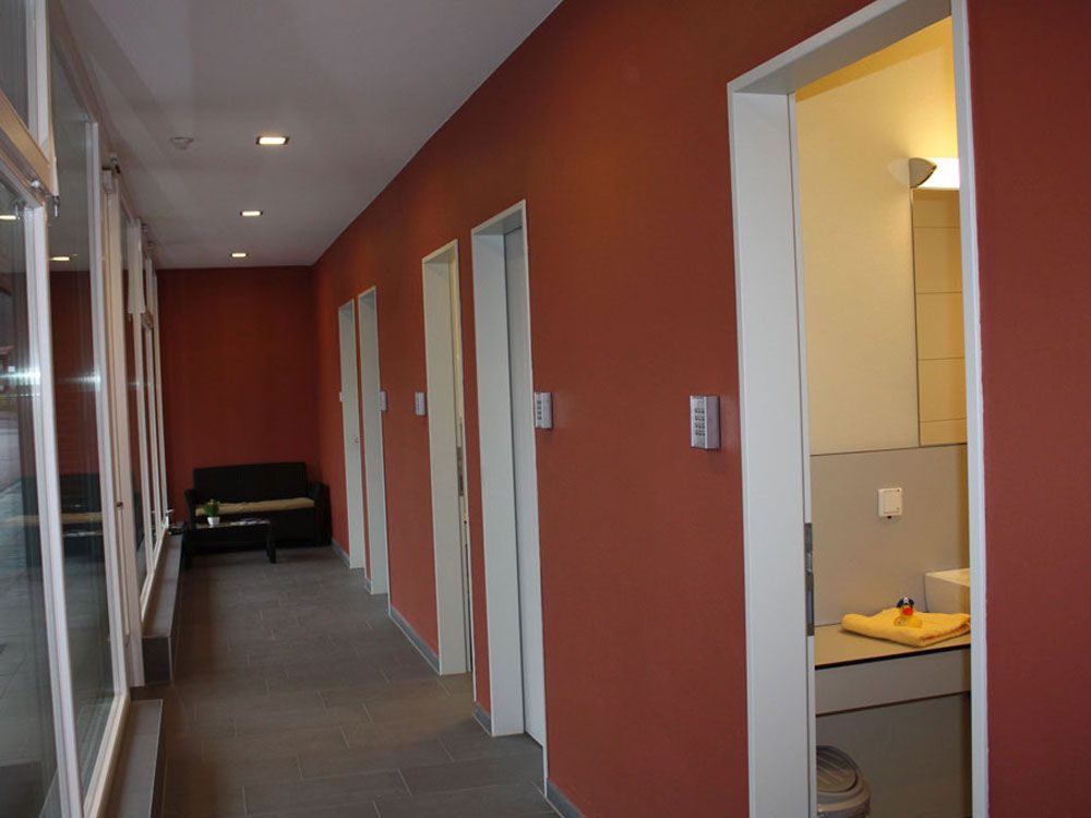Ein langer Flur mit roten Wänden und weißen Türen