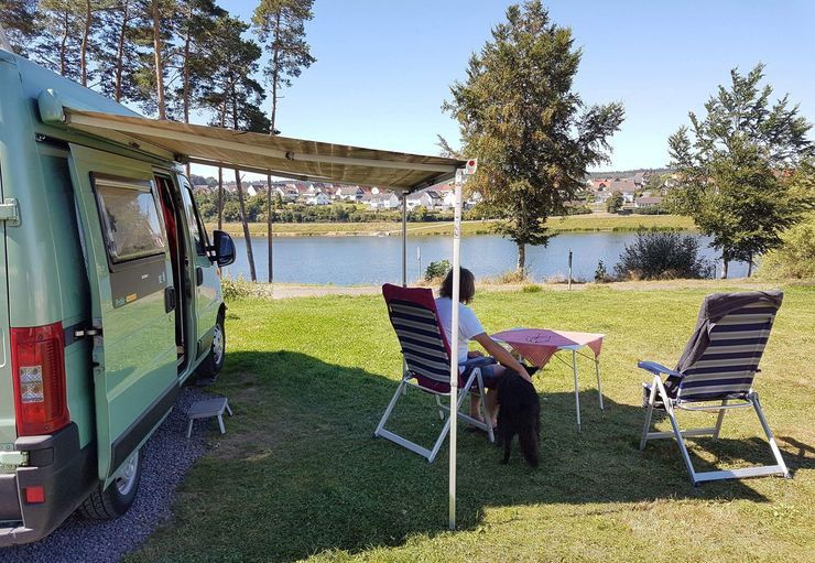 Eine Frau sitzt auf einem Stuhl vor einem Wohnmobil