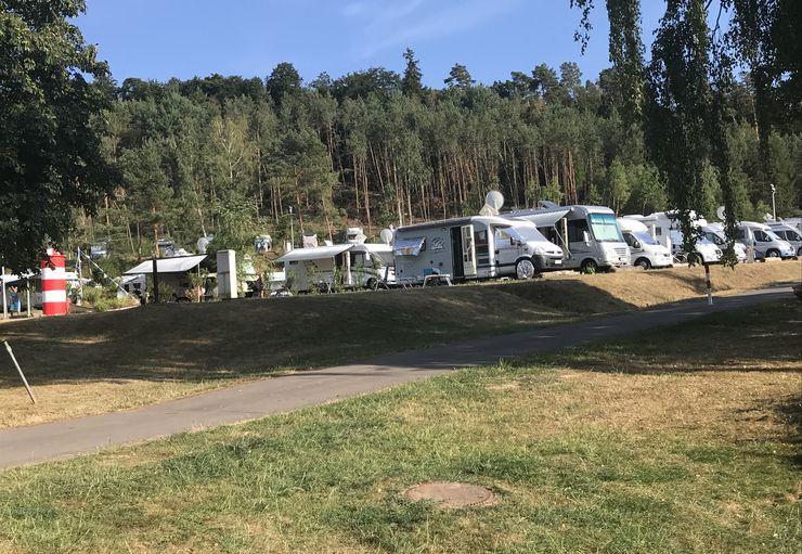 Eine Reihe von Wohnmobilen sind auf einer Wiese geparkt