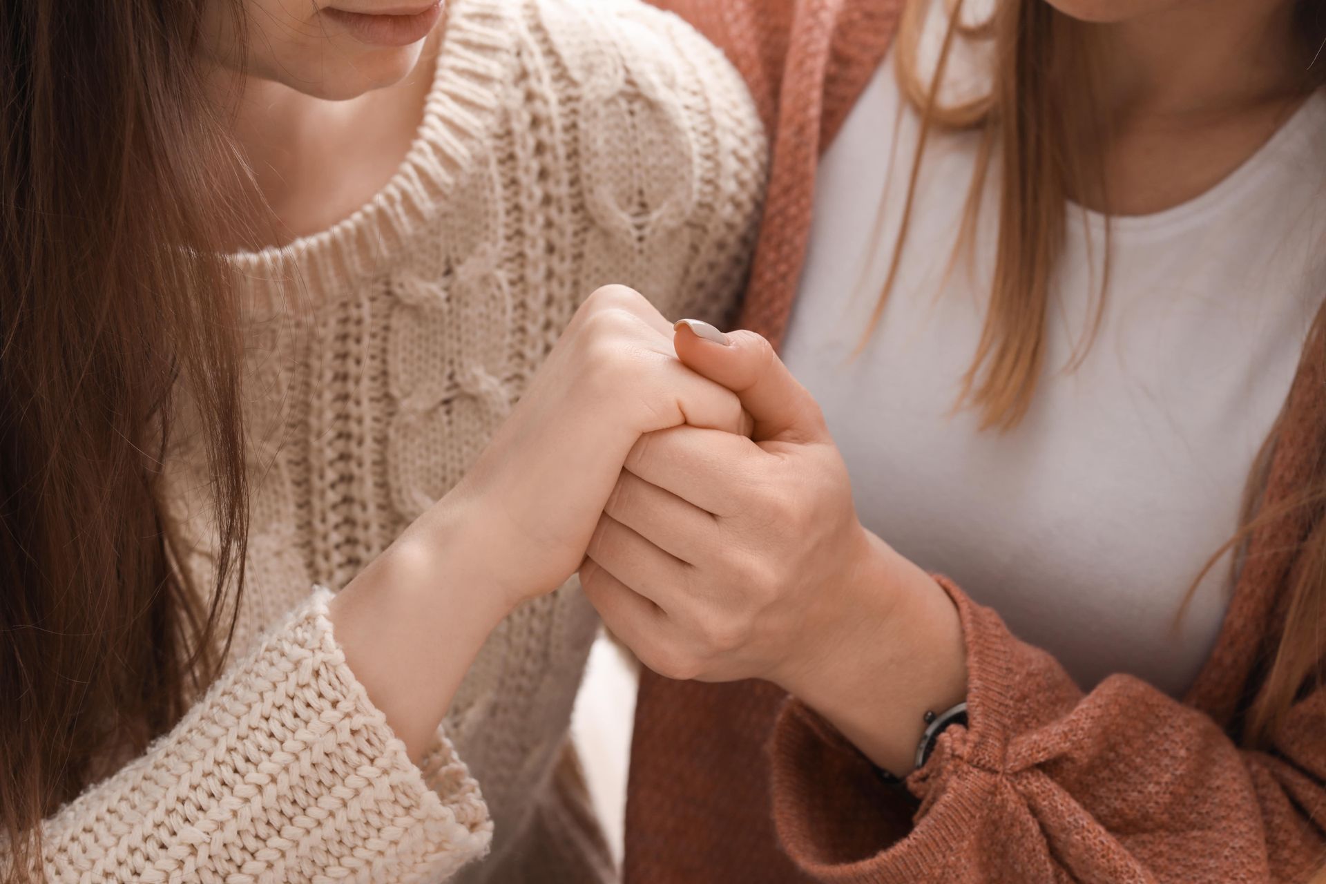 2 Frauen halten sich die Hand und unterstützen sich in Trauerzeiten