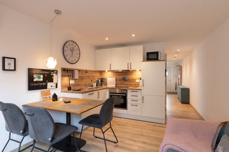 Eine Küche mit Tisch und Stühlen und einer Uhr an der Wand.