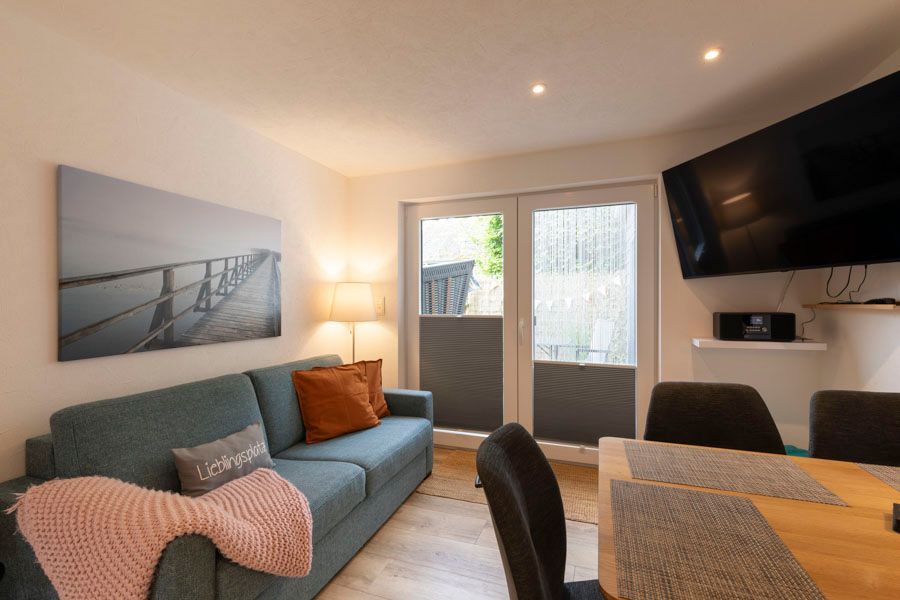 Ein Wohnzimmer mit Couch, Esstisch und Fernseher.