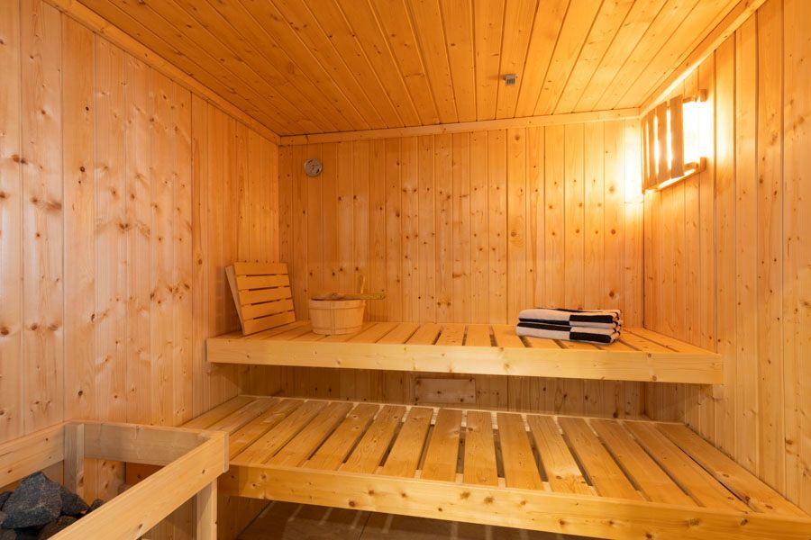 Eine Holzsauna mit Eimer und Handtüchern auf den Regalen.