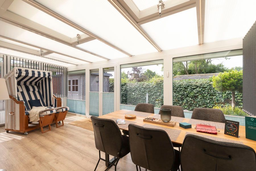 Ein Esszimmer mit Tisch und Stühlen und vielen Fenstern.