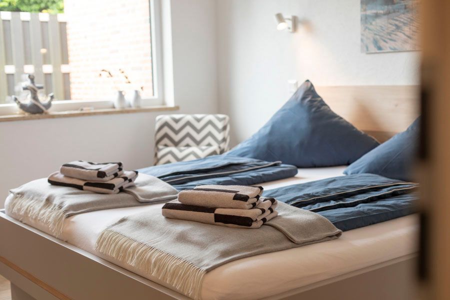 Ein Schlafzimmer mit zwei Betten, einem Stuhl und einem Fenster.