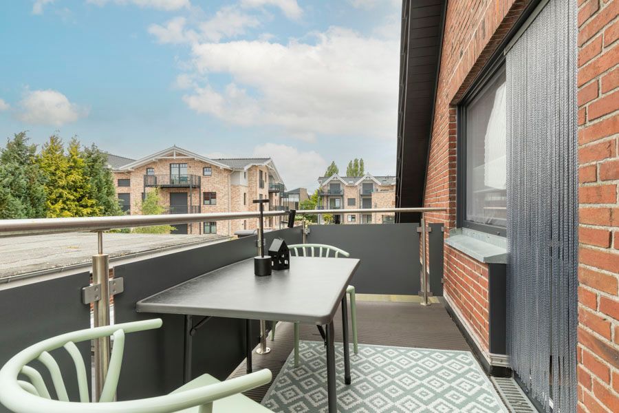 Ein Balkon mit Tisch und Stühlen vor einem Backsteingebäude.