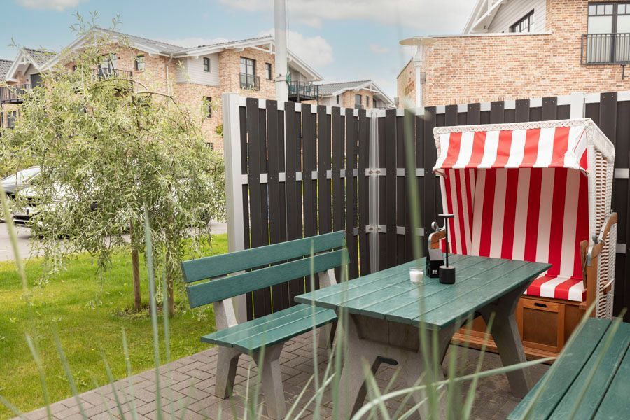 Ein grüner Tisch mit einem rot-weiß gestreiften Stuhl vor einem Zaun.