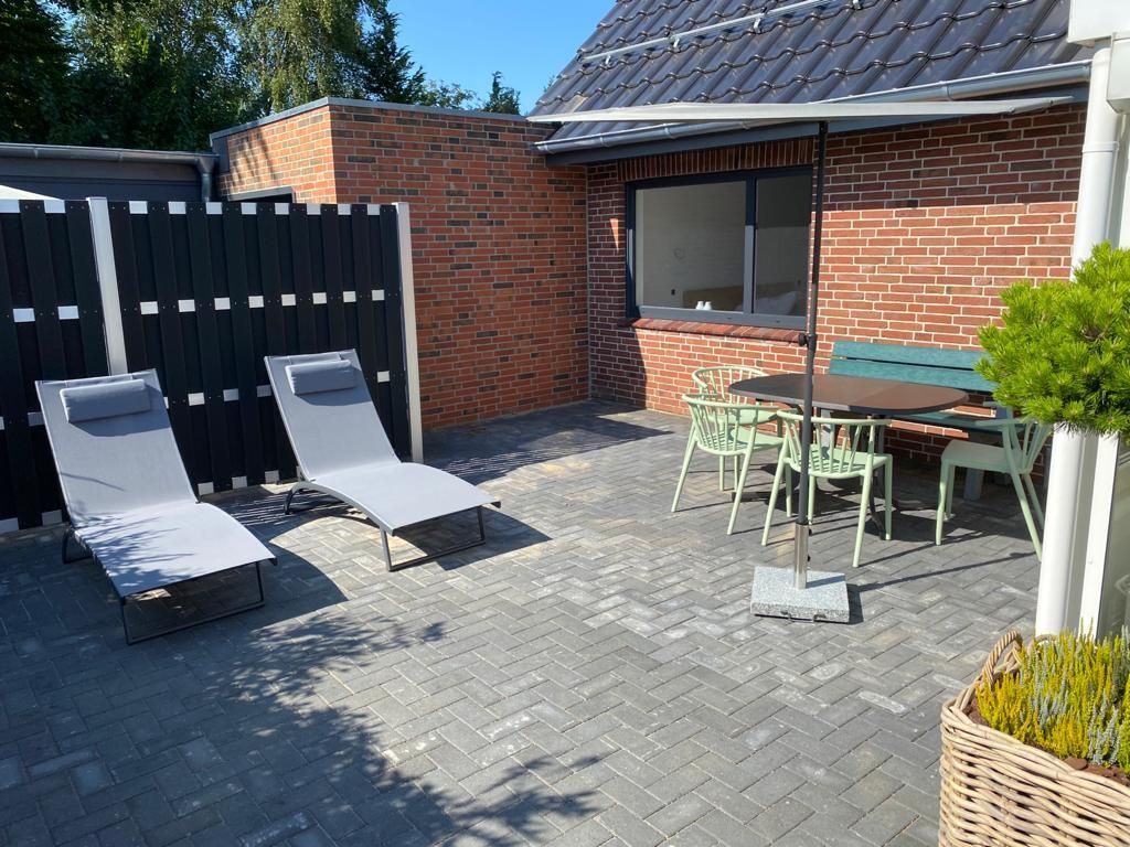 Eine Terrasse mit Stühlen und einem Tisch vor einem Backsteingebäude