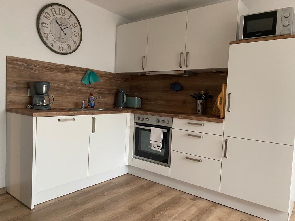 Eine Küche mit weißen Schränken und einer Uhr an der Wand.