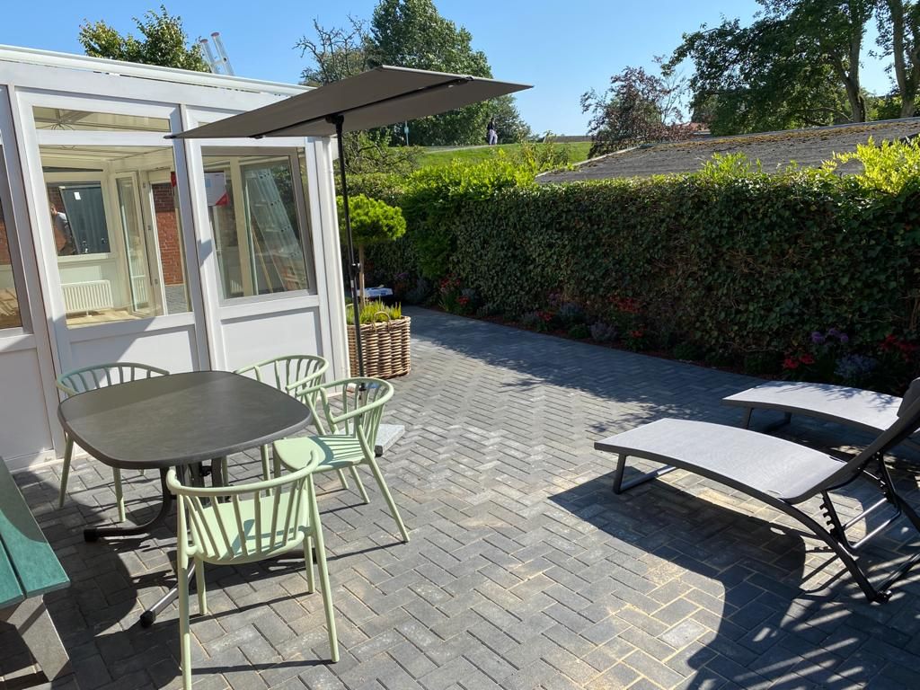 Eine Terrasse mit Tisch und Stühlen und einem Liegestuhl