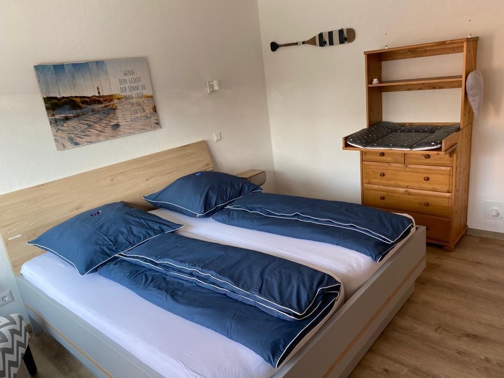 Ein Schlafzimmer mit einem Bett, einer Kommode und einem Gemälde an der Wand.
