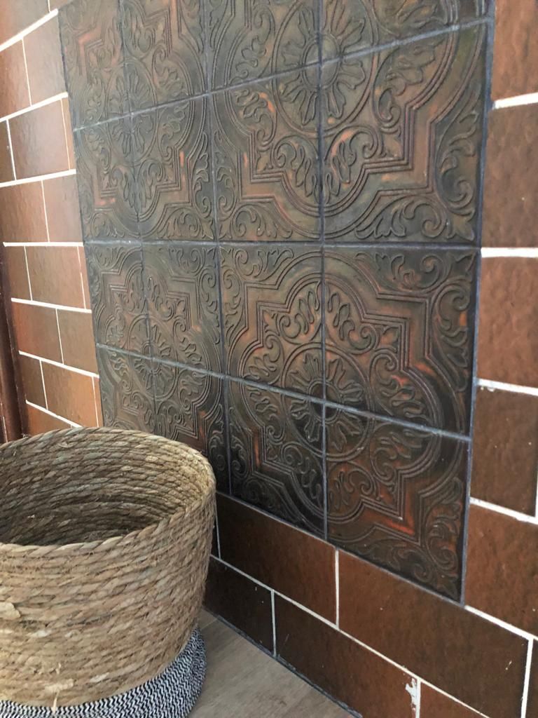 Vor einer Wand aus Fliesen steht ein Korb.