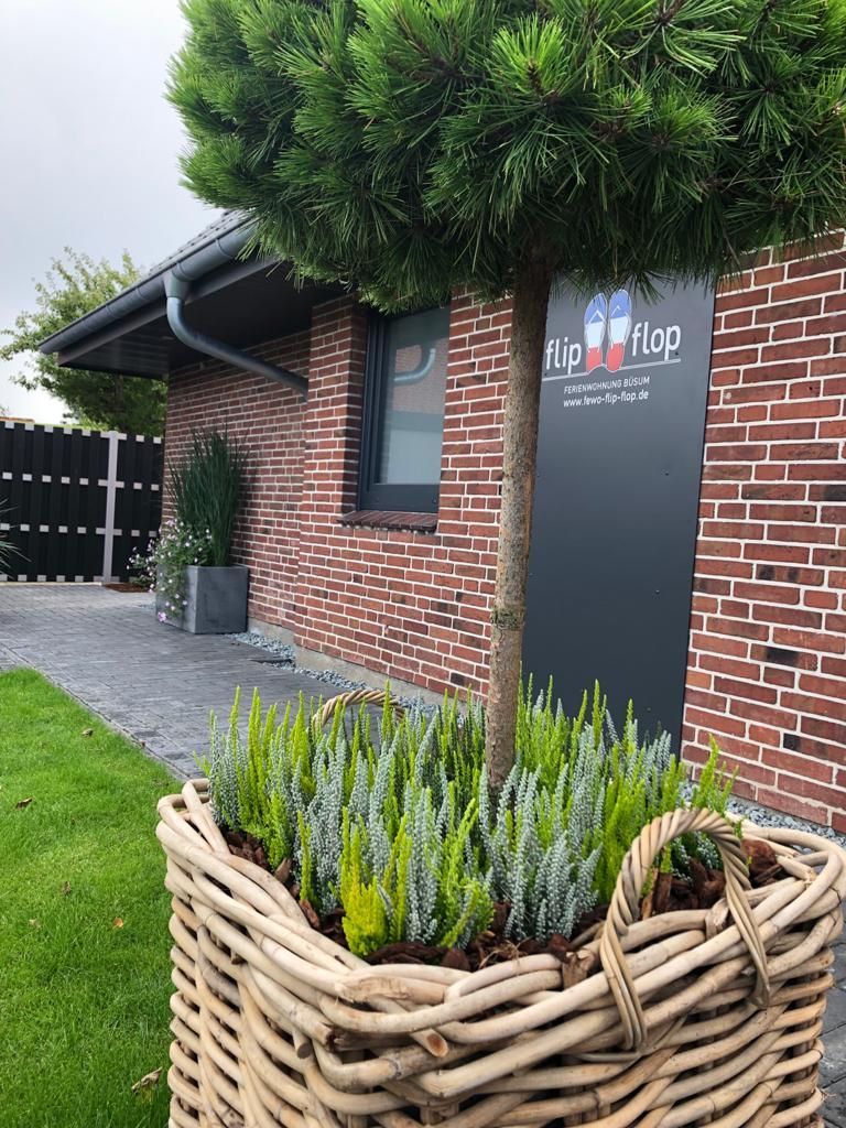 Vor einem Backsteingebäude steht ein mit Pflanzen gefüllter Weidenkorb.