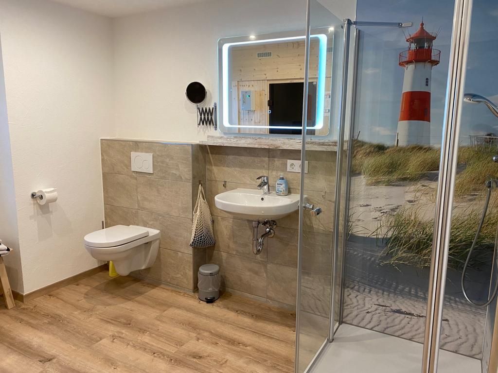 An der Wand im Badezimmer hängt ein Bild von einem Leuchtturm.