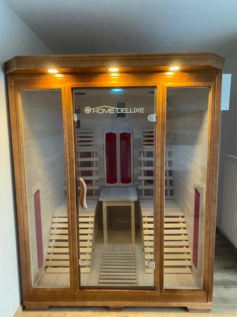 In einem Raum neben einer Treppe steht eine Holzsauna.