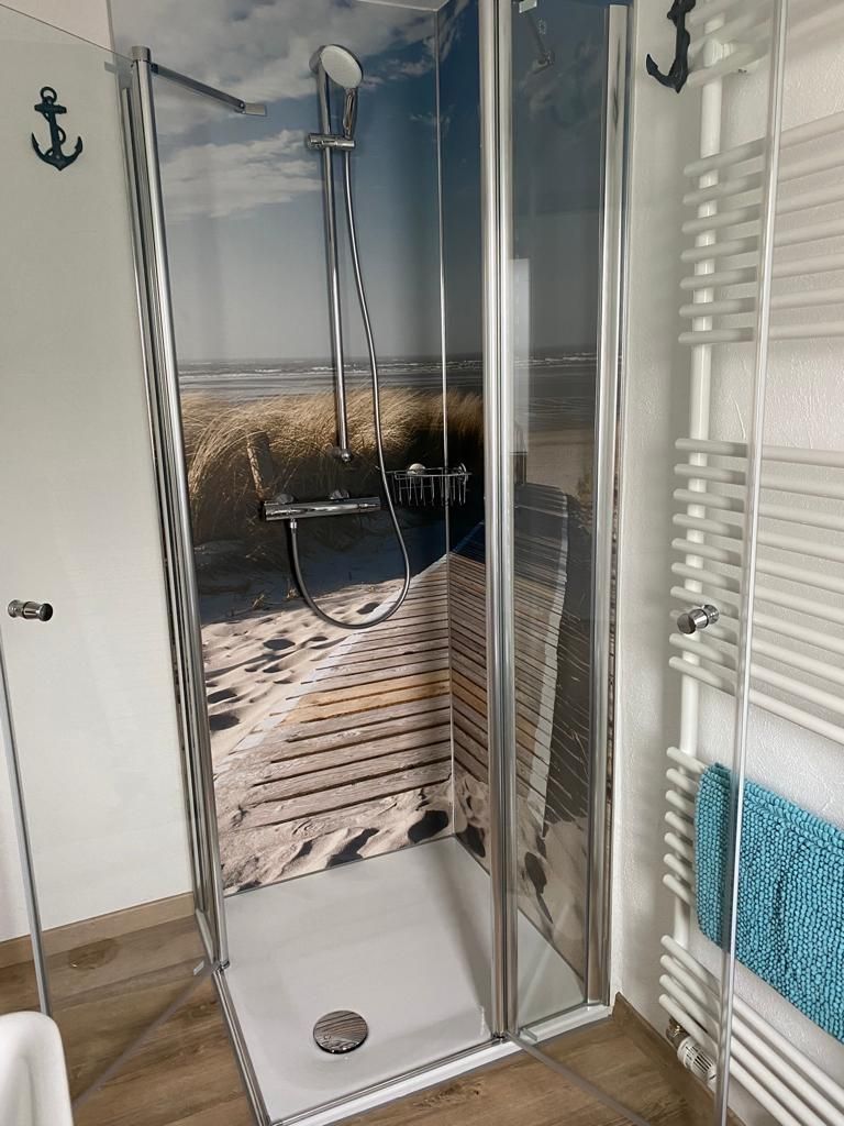 Ein Badezimmer mit ebenerdiger Dusche und Handtuchhalter.