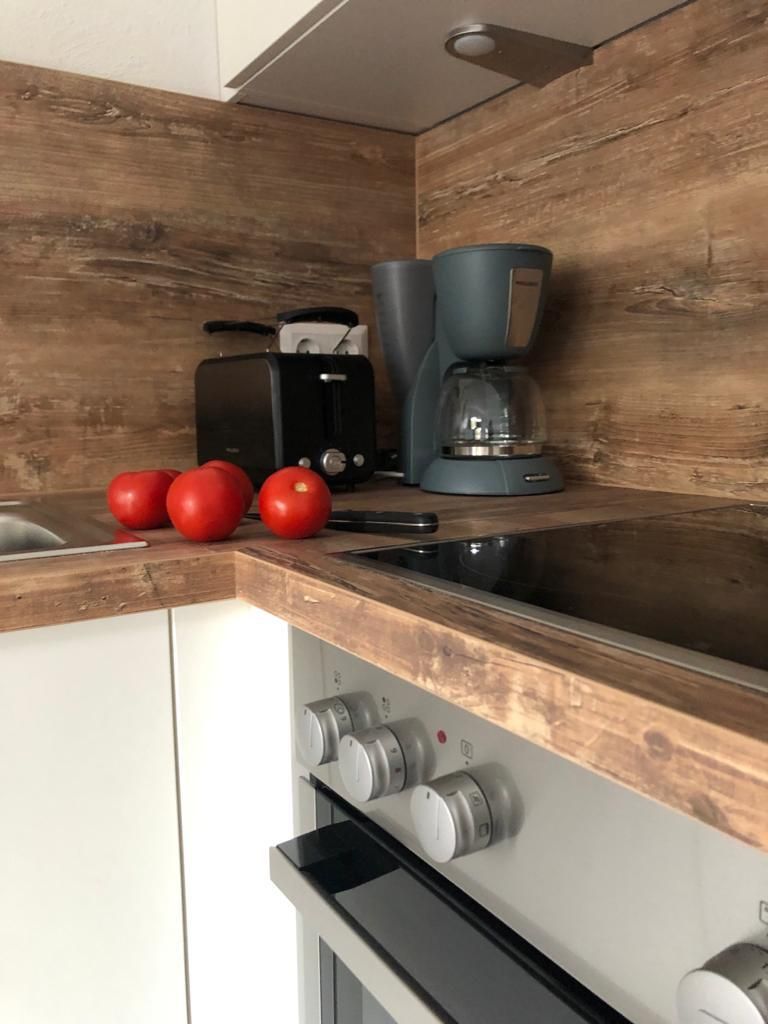 Eine Küche mit Kaffeemaschine, Toaster und Tomaten auf der Anrichte.