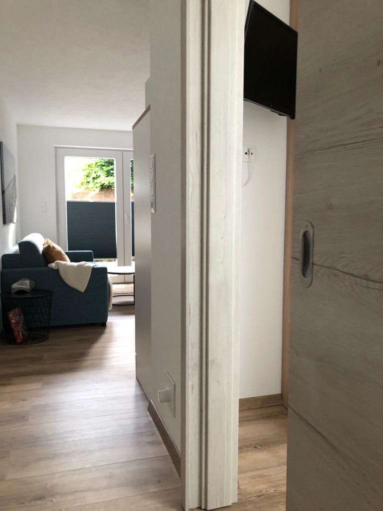 Ein Flur führt zu einem Wohnzimmer mit einem blauen Sofa.