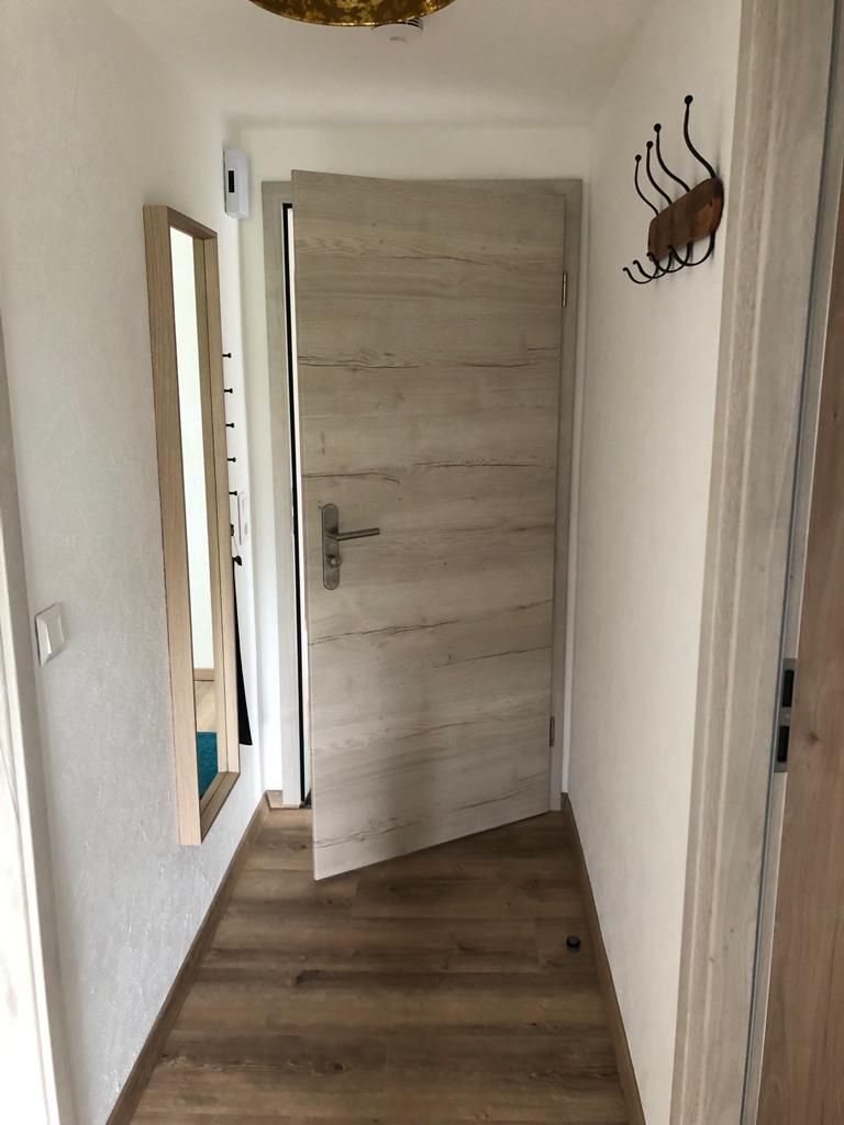 Ein Flur mit einer Tür und einem Spiegel an der Wand.