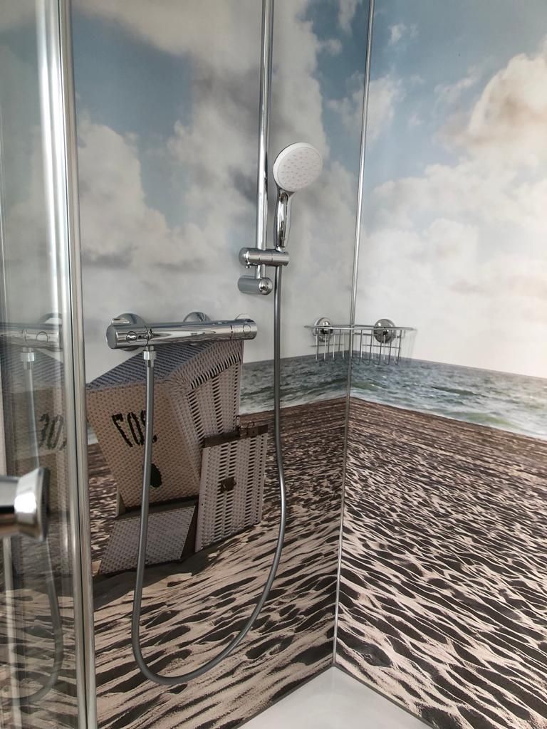 Eine Duschkabine mit einem Strandbild an der Wand.